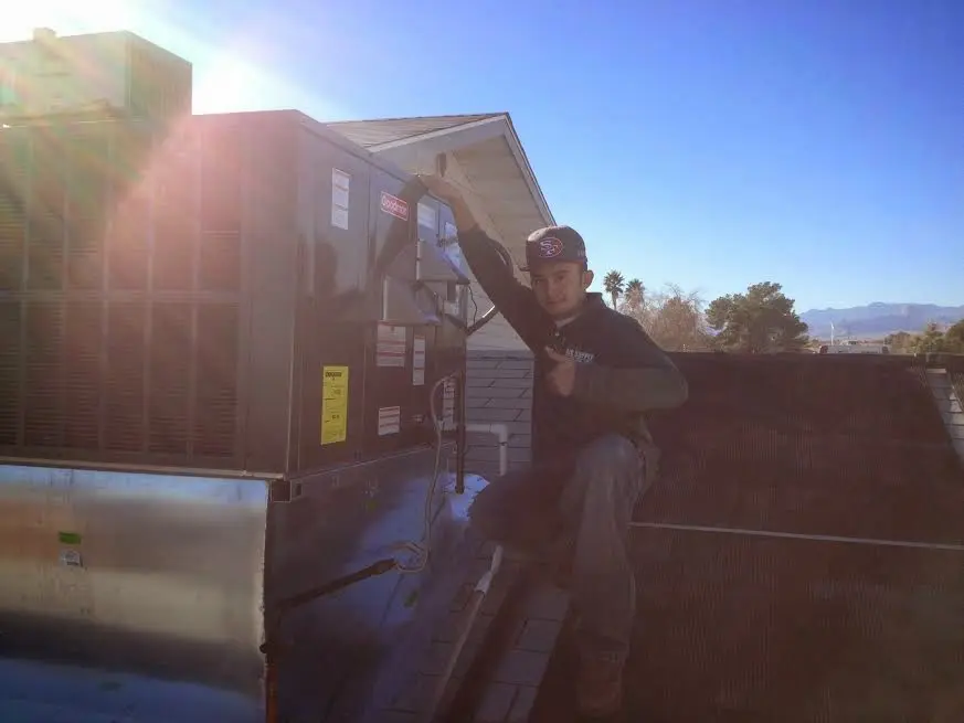 HVAC technician performing Air Duct Repair on a rooftop unit in Hanson